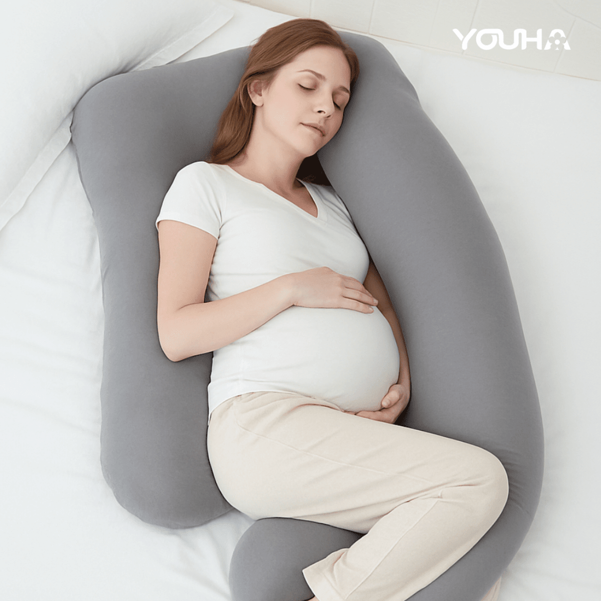 Zwangere moeder ligt ontspannen op haar zij op Youha zwangerschapskussen en geniet van optimale ondersteuning en comfort