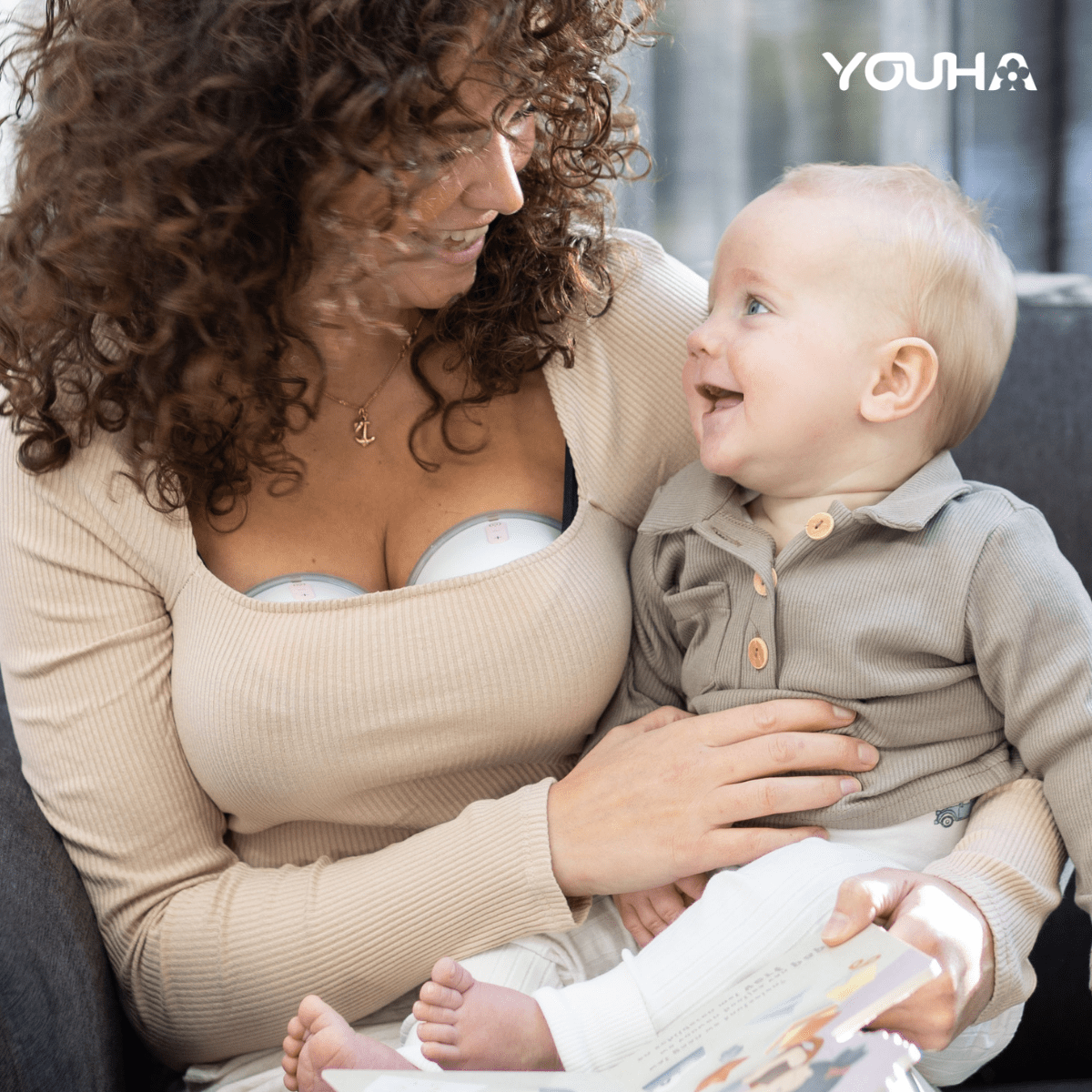 Moeder die kolft met een Youha borstkolf terwijl ze haar baby op schoot heeft