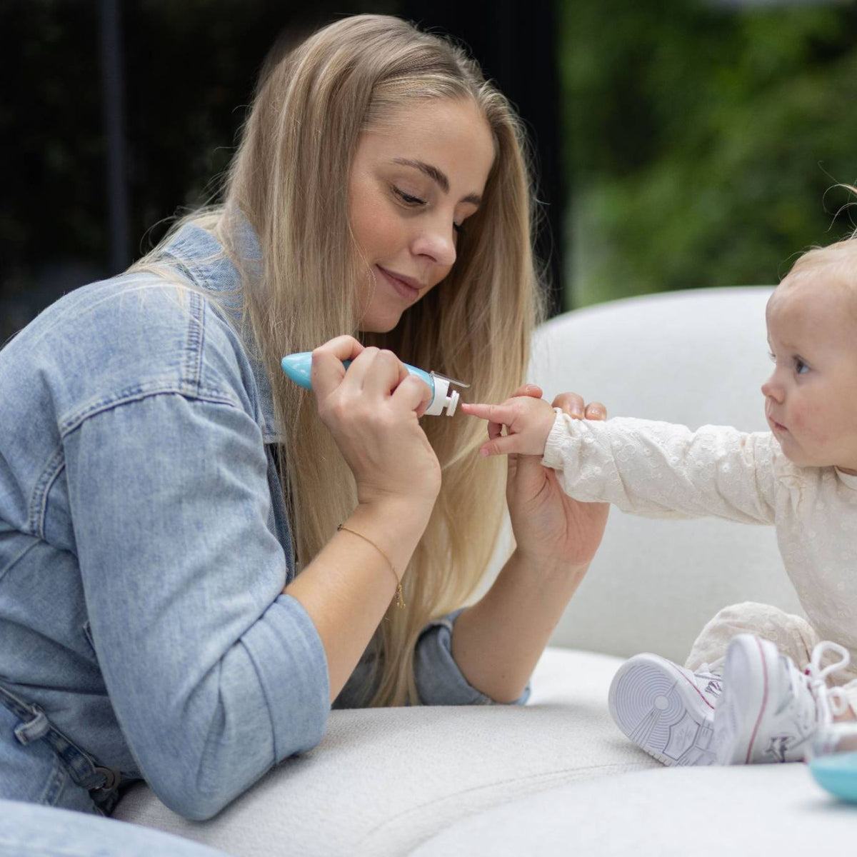 Een moeder vijlt veilig de nagels van haar baby met de Youha elektrische nagelvijl, ideaal voor pijnloze en snelle verzorging.