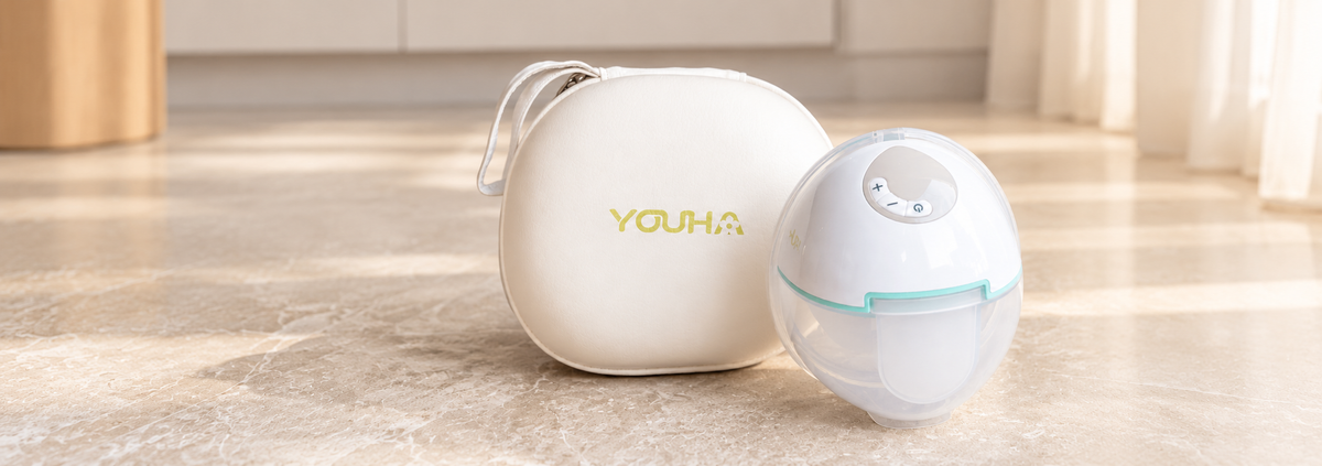 Youha Evera draadloze handsfree borstkolf met transparante opvangcup en wit beschermend opbergetui, gepresenteerd op een lichte ondergrond in een warme interieursetting.